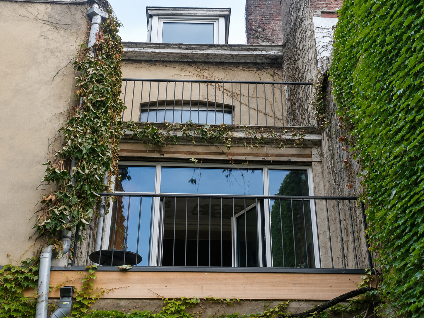 Garde-corps barreaudés en acier noir sur façade en vigne vierge, terrasse et balcon